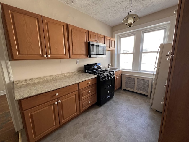 kitchen with radiator, sink, black gas stove, a textured ceiling, and white fridge