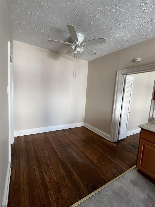 spare room with dark wood-type flooring, a textured ceiling, and ceiling fan