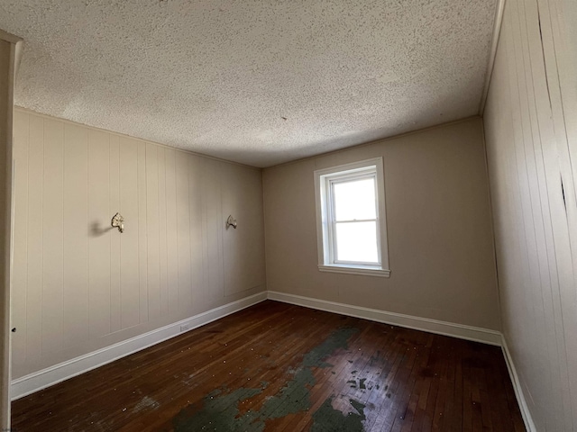 spare room featuring dark hardwood / wood-style floors and a textured ceiling