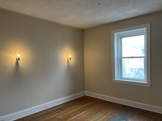 spare room featuring dark wood-type flooring and a textured ceiling