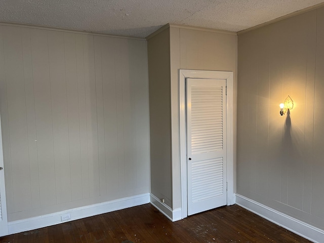 interior space with ornamental molding, a textured ceiling, and dark hardwood / wood-style flooring