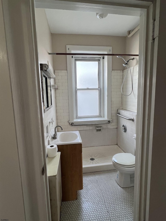 bathroom with vanity, toilet, and a tile shower