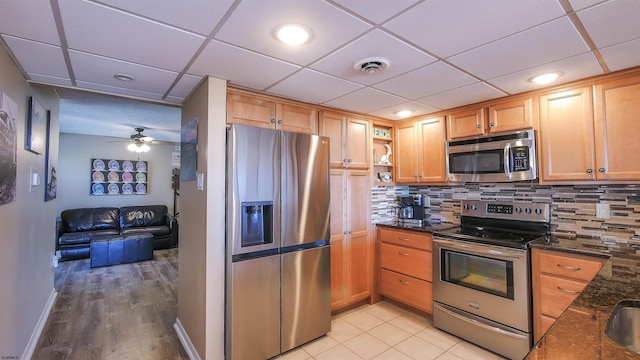 kitchen featuring tasteful backsplash, appliances with stainless steel finishes, dark stone countertops, and a drop ceiling