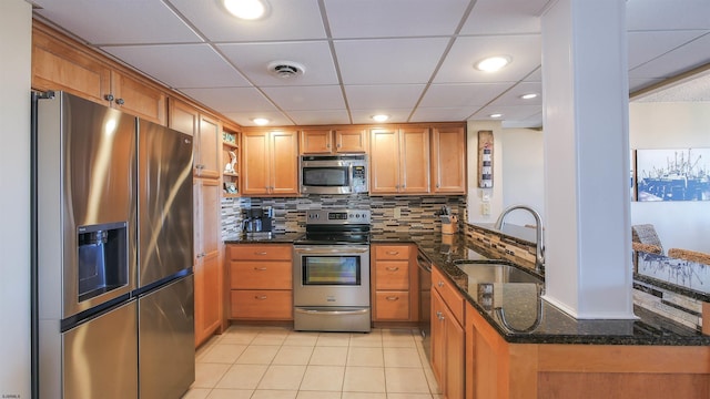 kitchen featuring sink, tasteful backsplash, dark stone countertops, appliances with stainless steel finishes, and kitchen peninsula