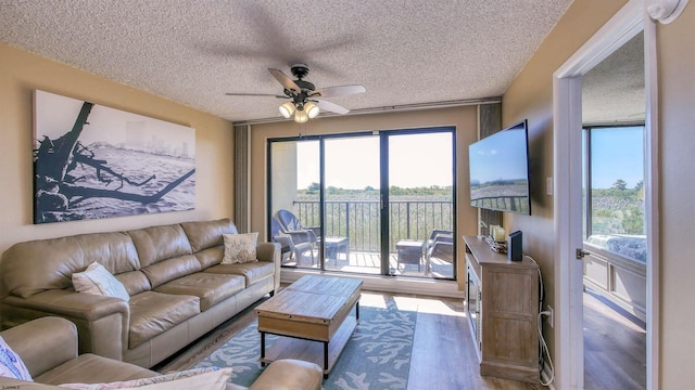 living room with a wealth of natural light, wood-type flooring, a textured ceiling, and ceiling fan