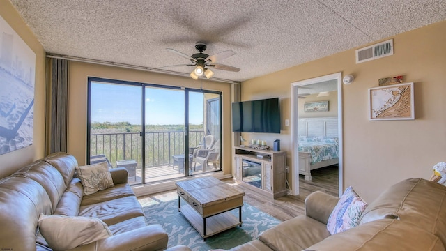 living room featuring hardwood / wood-style flooring, a textured ceiling, and ceiling fan