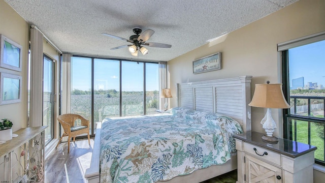 bedroom featuring ceiling fan, hardwood / wood-style flooring, a wall of windows, and a textured ceiling