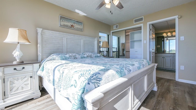 bedroom featuring ensuite bathroom, hardwood / wood-style flooring, ceiling fan, a textured ceiling, and a closet