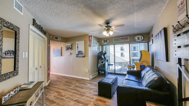 living room featuring wood-type flooring, ceiling fan, a textured ceiling, and a baseboard radiator