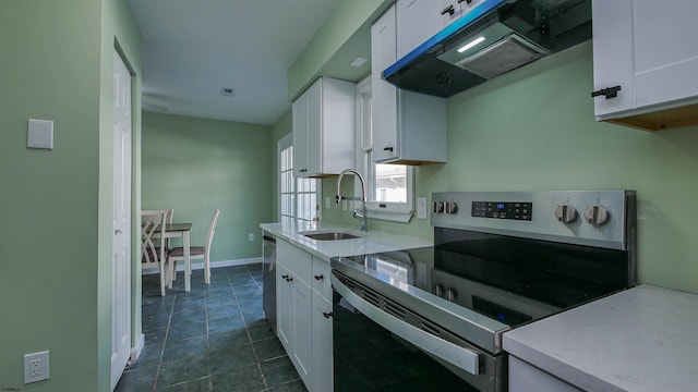 kitchen with sink, dark tile patterned floors, appliances with stainless steel finishes, white cabinetry, and exhaust hood