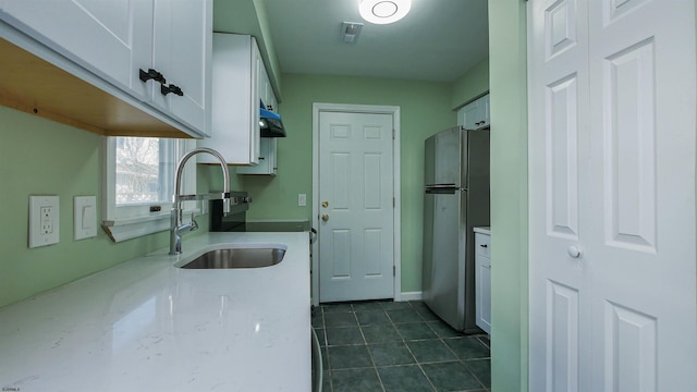 kitchen with sink, dark tile patterned floors, stainless steel fridge, and white cabinets