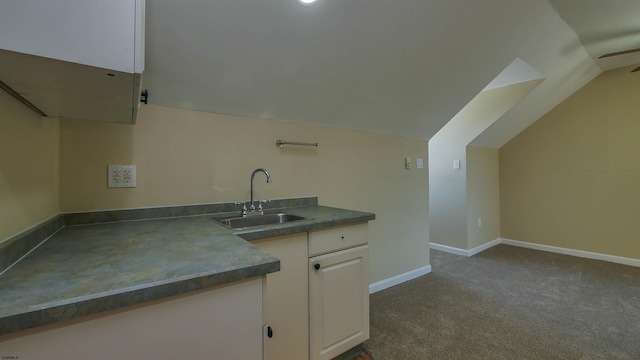 kitchen with light colored carpet, lofted ceiling, sink, and white cabinets