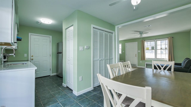 dining room featuring sink, dark tile patterned floors, and ceiling fan