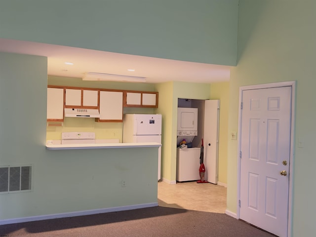 kitchen featuring stacked washer and dryer, white cabinetry, white refrigerator, light carpet, and kitchen peninsula