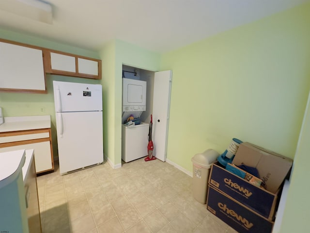 kitchen with stacked washing maching and dryer, white fridge, and white cabinets