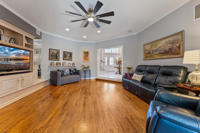 living room with crown molding, light hardwood / wood-style floors, and ceiling fan