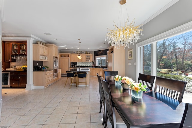 tiled dining area with wine cooler, a notable chandelier, ornamental molding, and ornate columns