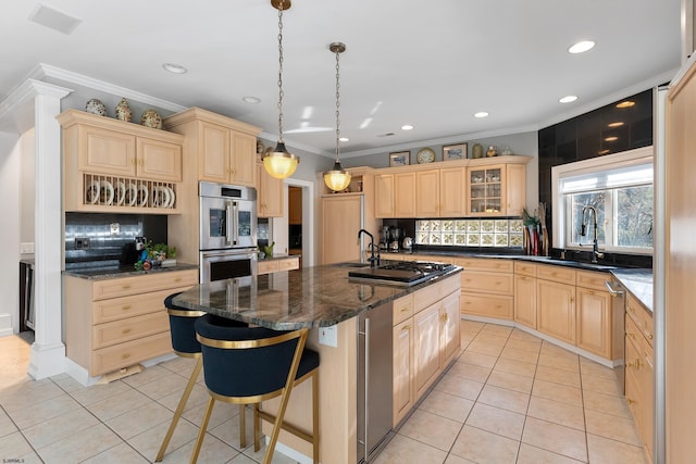 kitchen featuring light tile patterned floors, appliances with stainless steel finishes, dark stone countertops, a kitchen breakfast bar, and an island with sink