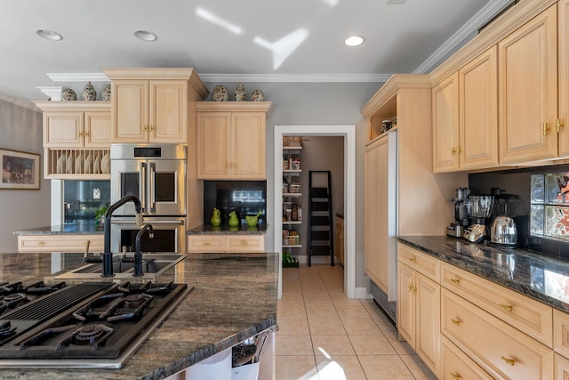 kitchen with light tile patterned flooring, ornamental molding, stainless steel appliances, and dark stone countertops