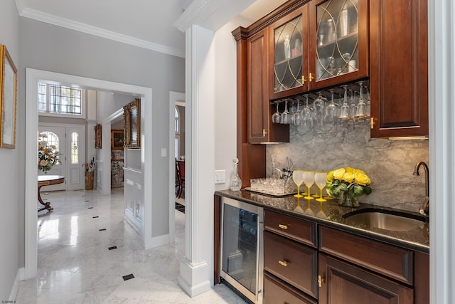 bar featuring sink, tasteful backsplash, dark stone countertops, ornamental molding, and beverage cooler