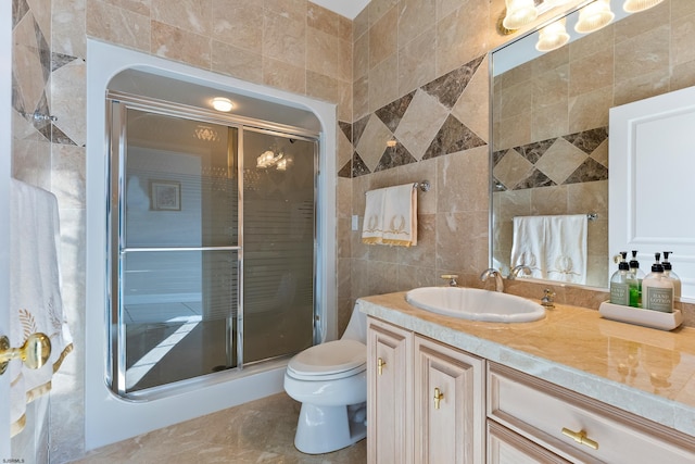 bathroom featuring toilet, tile walls, vanity, and a shower with shower door