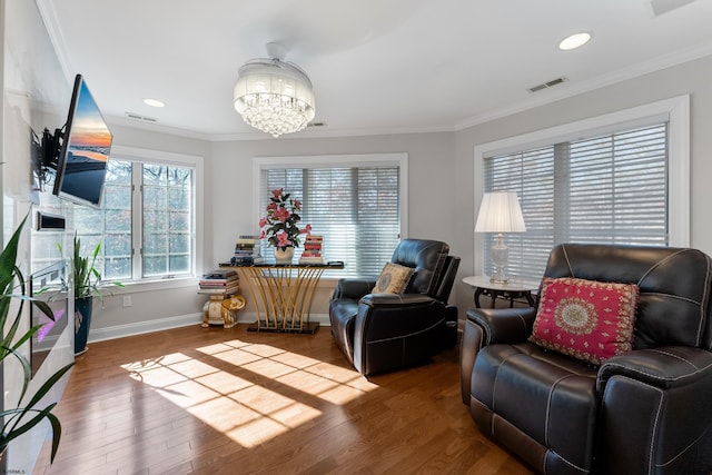 sitting room with crown molding, a chandelier, and hardwood / wood-style flooring