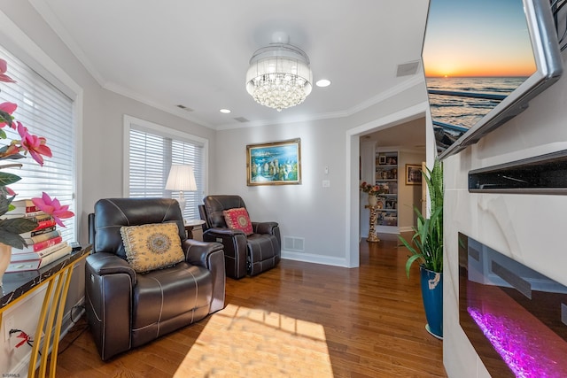 living area featuring hardwood / wood-style flooring, ornamental molding, and an inviting chandelier