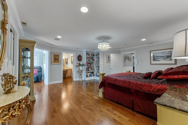 bedroom featuring hardwood / wood-style flooring, crown molding, a chandelier, and ensuite bath