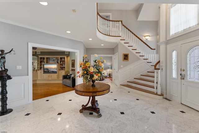 foyer with a towering ceiling and ornamental molding