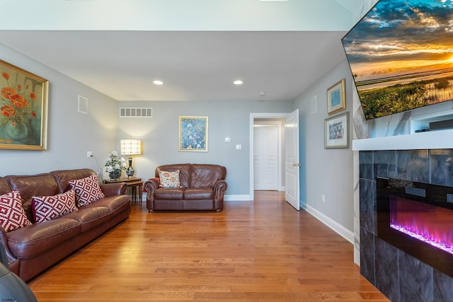 living room with a tiled fireplace and hardwood / wood-style floors