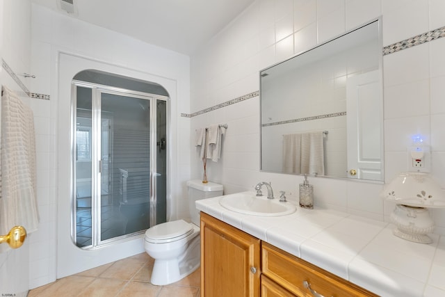 bathroom with tile walls, vanity, an enclosed shower, tile patterned floors, and toilet