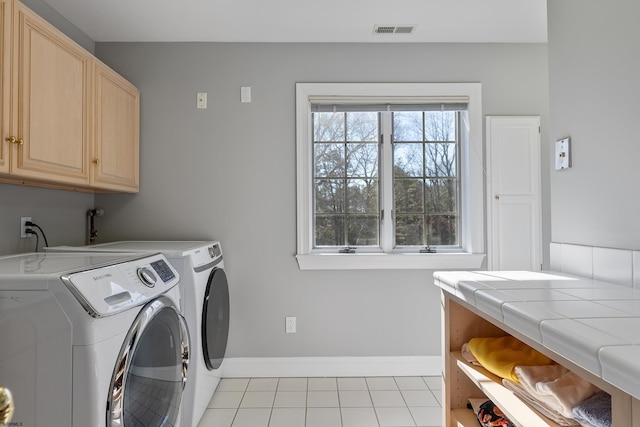 laundry room with independent washer and dryer, cabinets, and light tile patterned floors