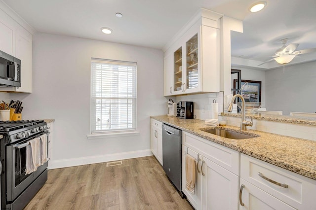 kitchen with sink, light hardwood / wood-style flooring, appliances with stainless steel finishes, light stone countertops, and white cabinets