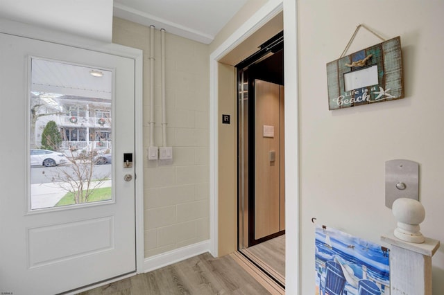 doorway to outside featuring elevator and light hardwood / wood-style floors