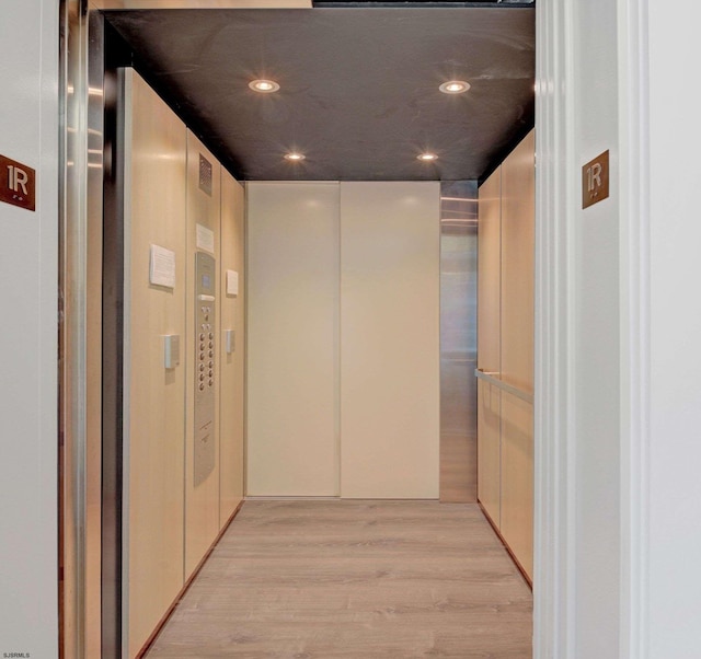 corridor featuring elevator and light hardwood / wood-style floors