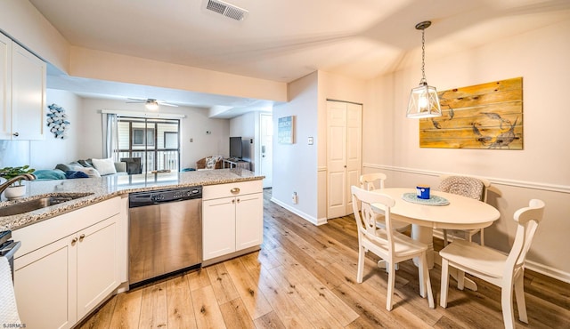 kitchen with decorative light fixtures, white cabinetry, sink, stainless steel dishwasher, and light stone countertops