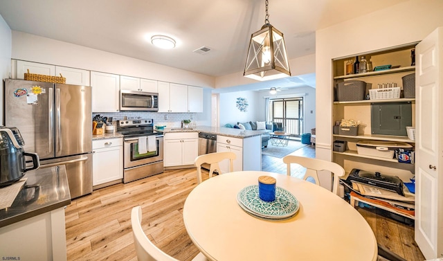 kitchen with white cabinetry, hanging light fixtures, light hardwood / wood-style flooring, appliances with stainless steel finishes, and kitchen peninsula