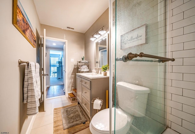 bathroom with vanity, a shower with door, tile patterned floors, and toilet