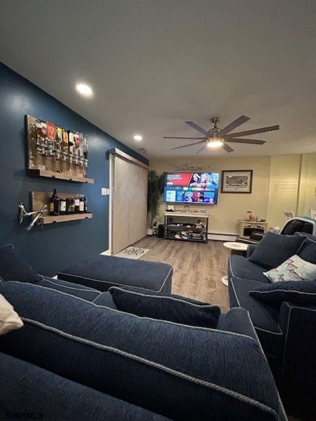 living room featuring wood-type flooring, a baseboard radiator, and ceiling fan