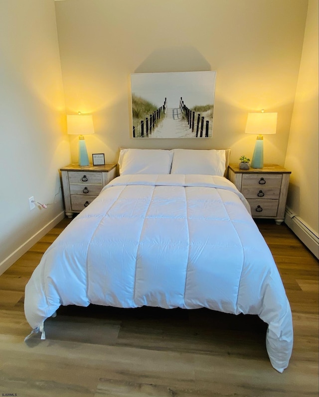 bedroom with a baseboard radiator and dark hardwood / wood-style floors