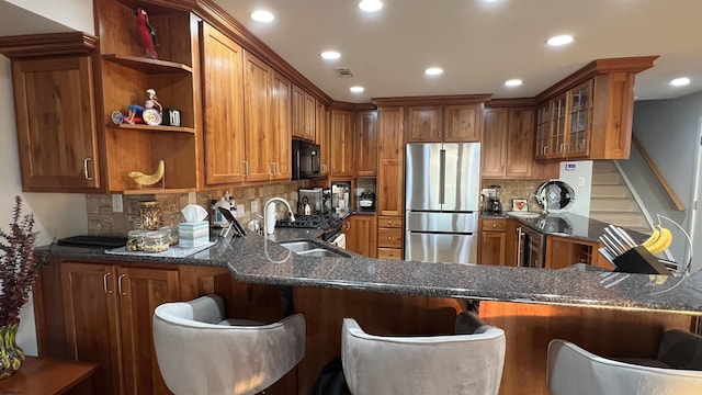 kitchen featuring a breakfast bar area, dark stone countertops, stainless steel fridge, kitchen peninsula, and decorative backsplash