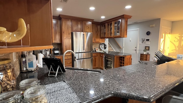 kitchen featuring stainless steel fridge, a breakfast bar area, backsplash, beverage cooler, and kitchen peninsula