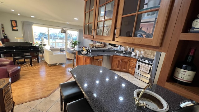 kitchen with stainless steel appliances, dark stone countertops, sink, and light tile patterned floors