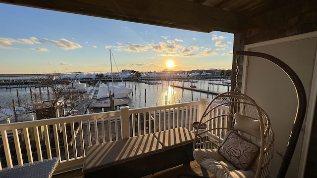 balcony at dusk featuring a water view