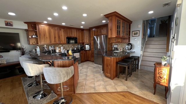 kitchen featuring light tile patterned floors, appliances with stainless steel finishes, backsplash, a kitchen breakfast bar, and kitchen peninsula