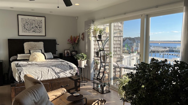 bedroom with a water view, ceiling fan, and wood-type flooring