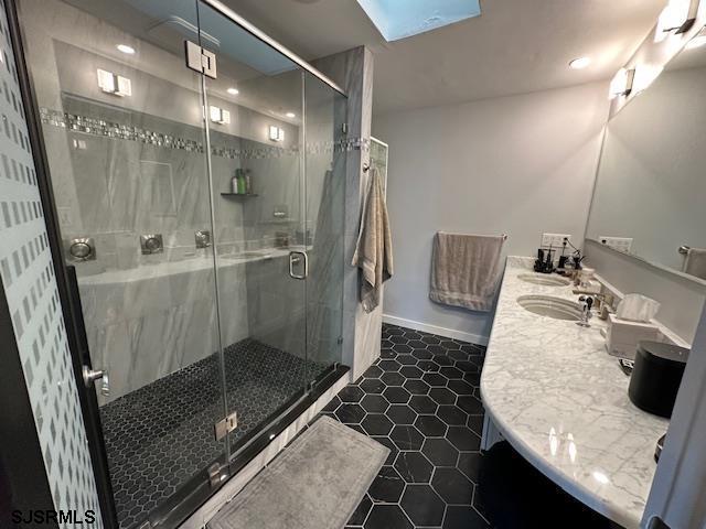 bathroom with vanity, a skylight, tile patterned floors, and walk in shower