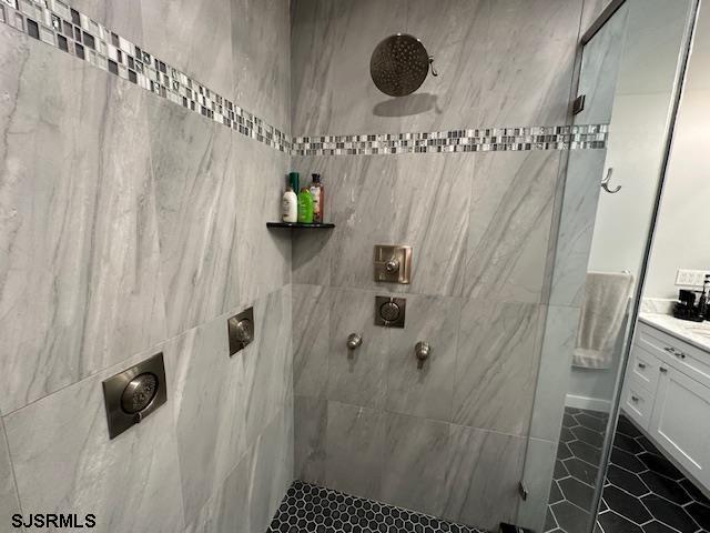 bathroom with tile patterned floors, vanity, and a tile shower