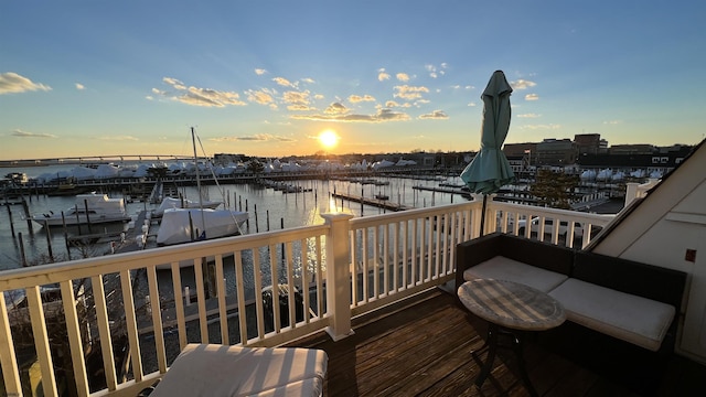 deck at dusk featuring a dock and a water view