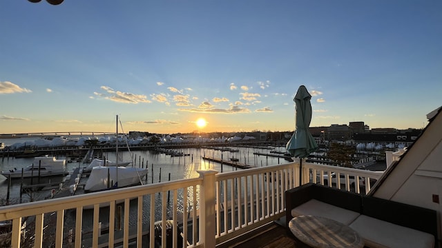 deck at dusk with a water view and a boat dock